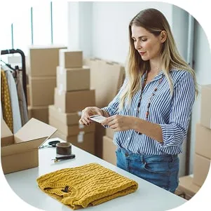 Woman packing orders of clothes into boxes